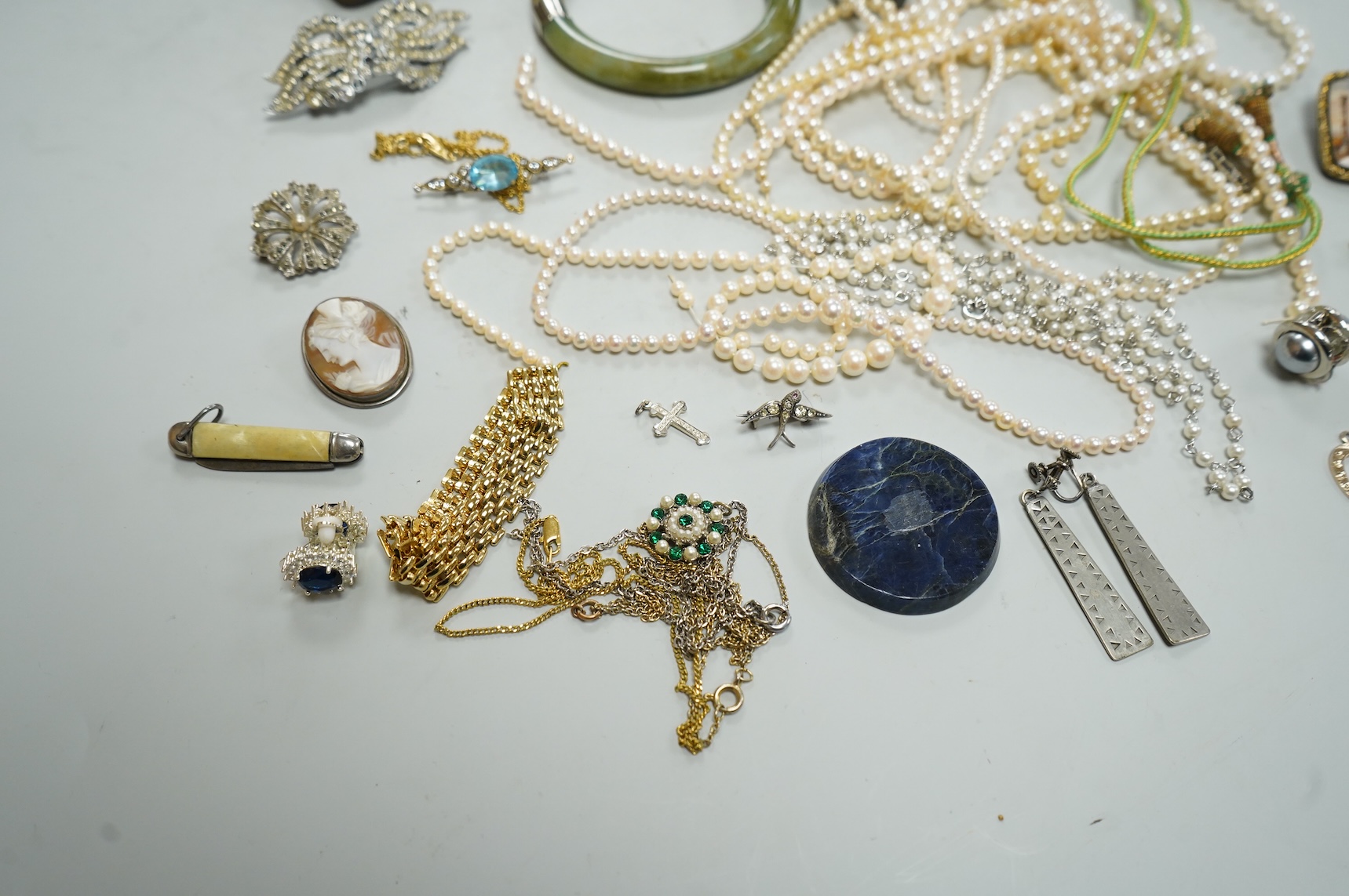 A collection of assorted jewellery including a jade bangle, cultured pearl necklaces and a diamond set yellow metal and quartz ring.